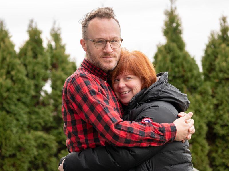 Rachel and Jason hugging outside at a christmas tree farm