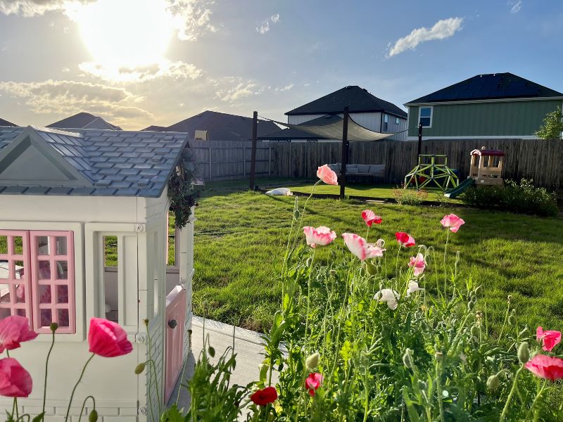 Backyard of Austin, TX adoptive family, with flowers and a kids playhouse