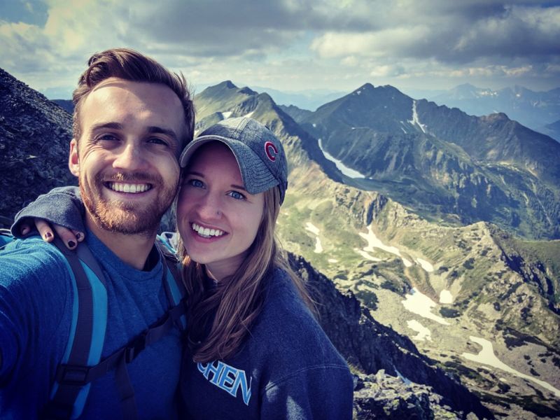 Active couple hoping to adopt, hiking with mountains in the background