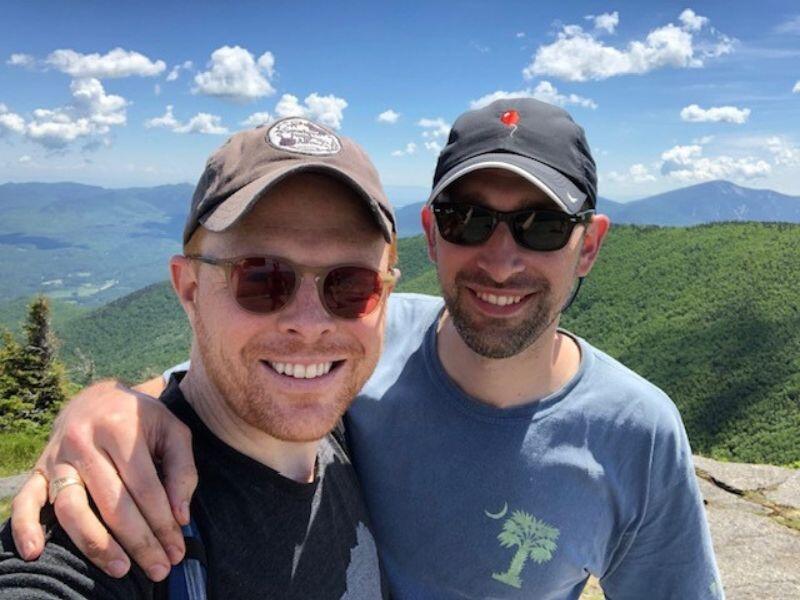 Gay adoptive dads on an outdoor adventure with mountain view in background