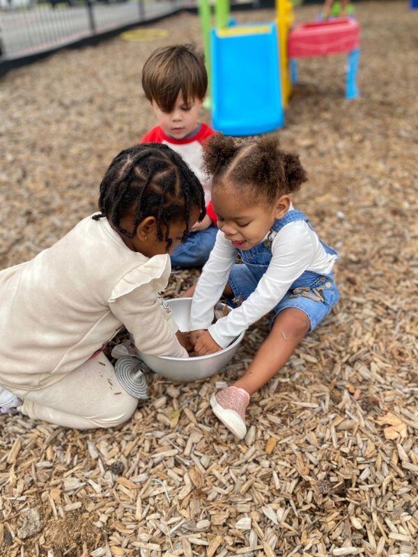 Black female toddler playing with diverse friends at a playground