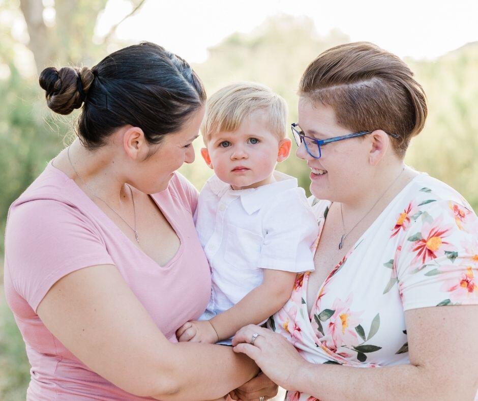 Gay women holding their adopted child.