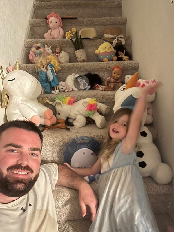 Adoptive dad with daughter playing with lovies on staircase