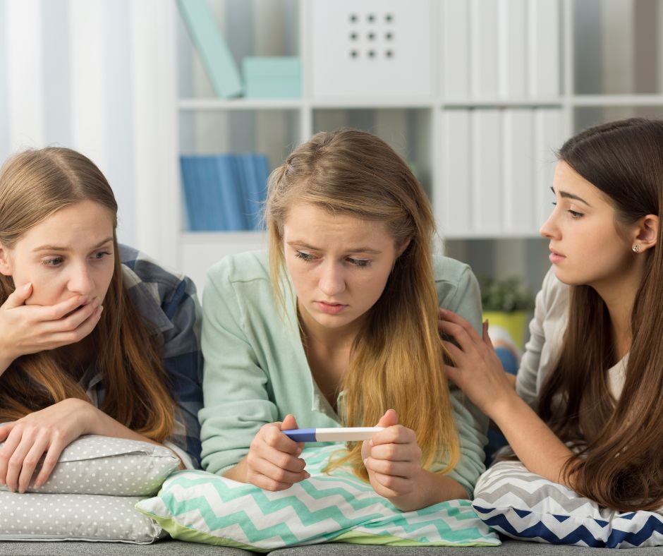 scared teen looking at positive pregnancy test with friends
