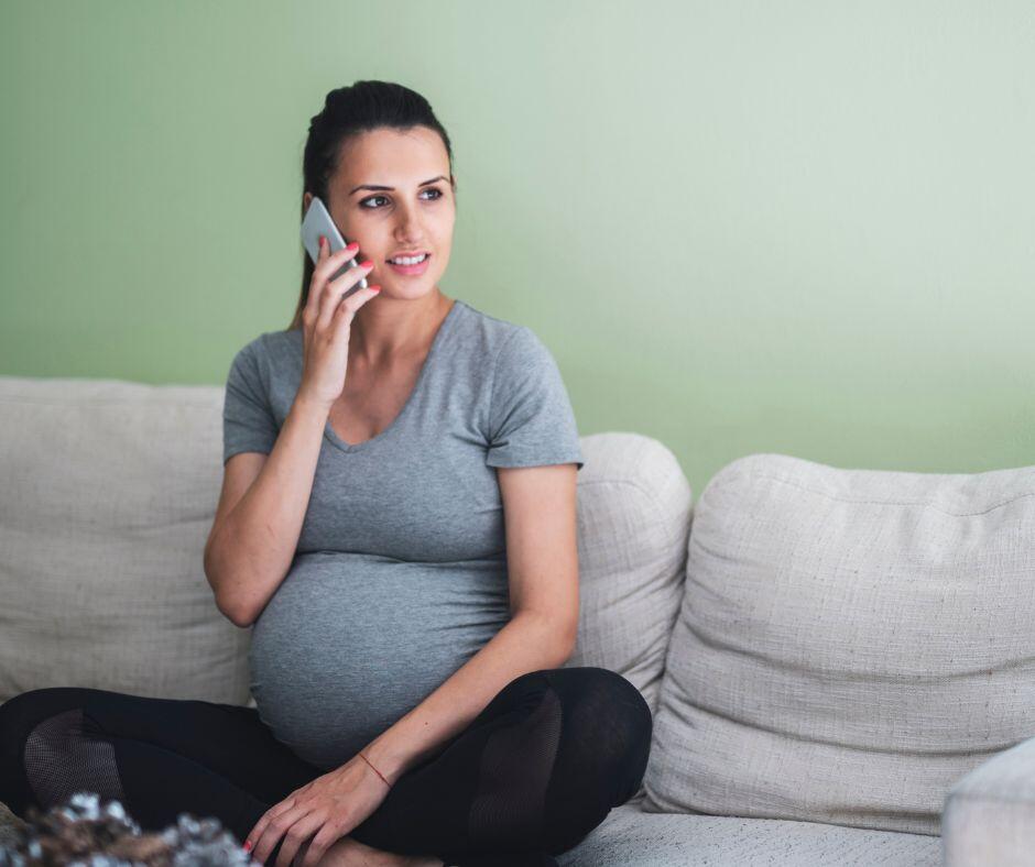 Pregnant woman making a phone call to learn about the adoption process