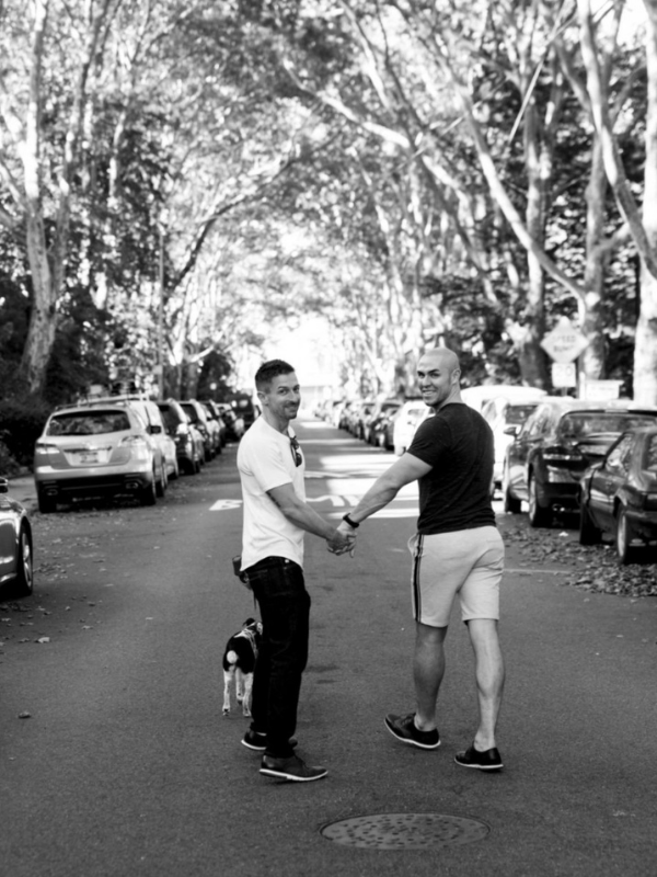 Brian and Jesus, an Austin couple looking to adopt a baby, holding hands while walking small dog.