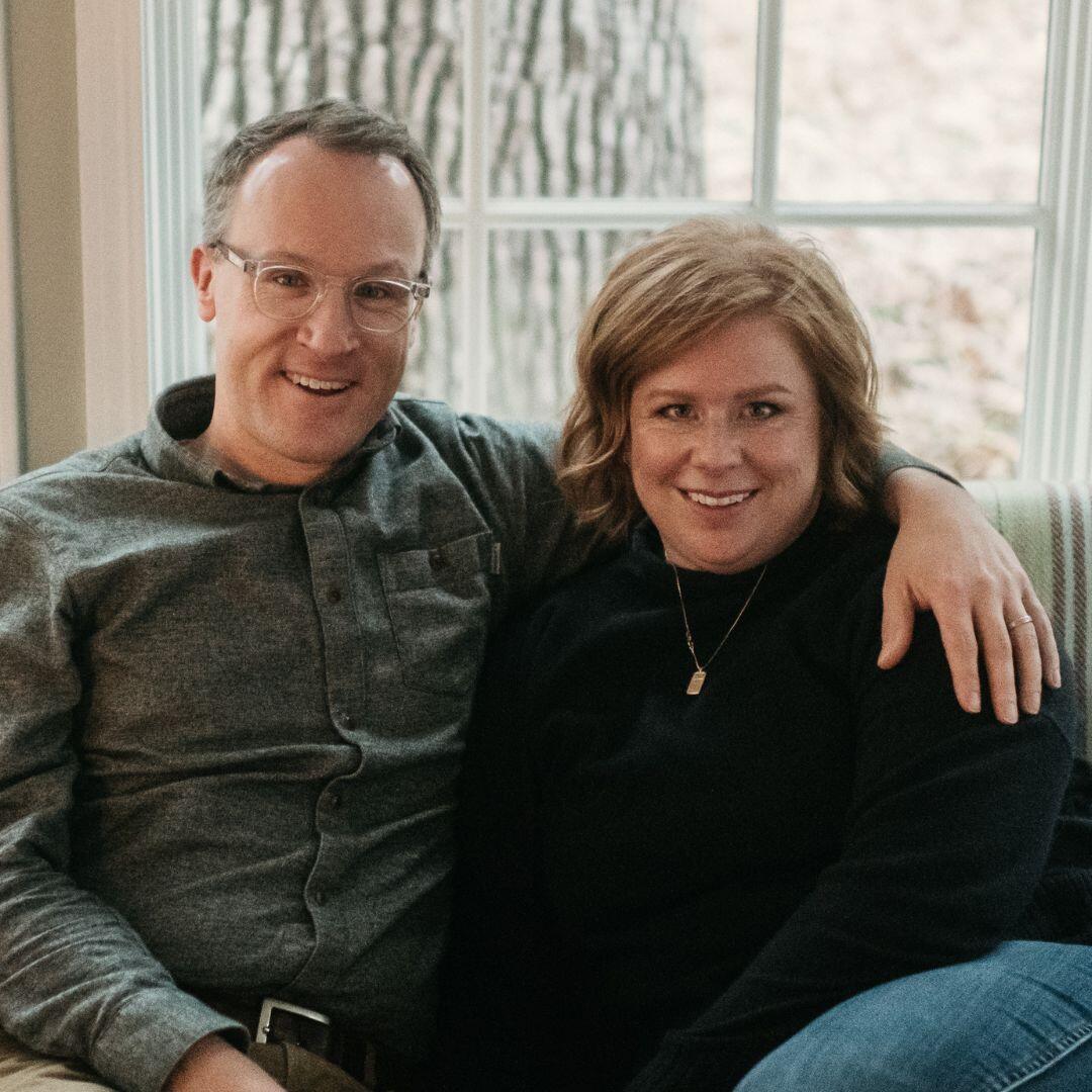 Prospective adoptive parents Rachel and Jason, posing on the couch in their home